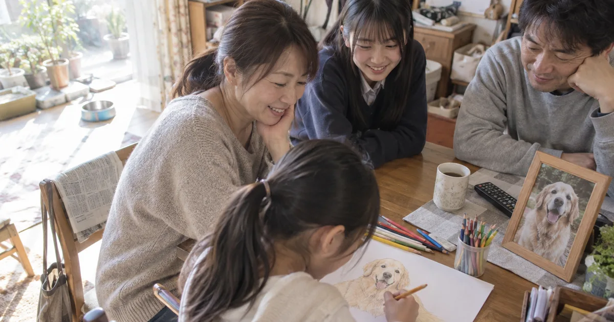 ゴールデンレトリバーの絵を描く子どもと見守る10代の娘がいる家族